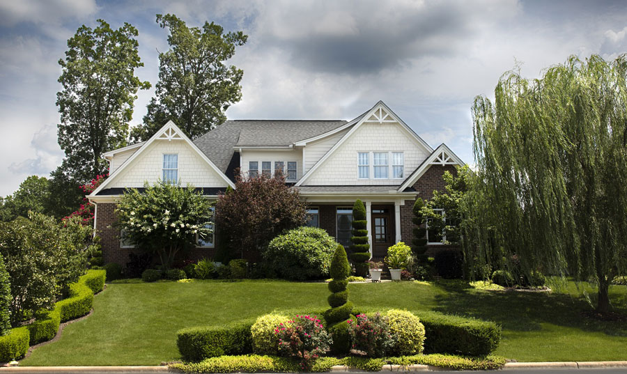 This images focuses on a white and brown house, with an immaculate yard. At the top of the house, under the roof are two pvc gable brackets.