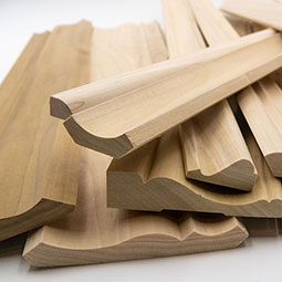 Variety of hardwood moulding pieces stacked together, showcasing intricate profiles and natural wood grains, ideal for enhancing interior design projects.